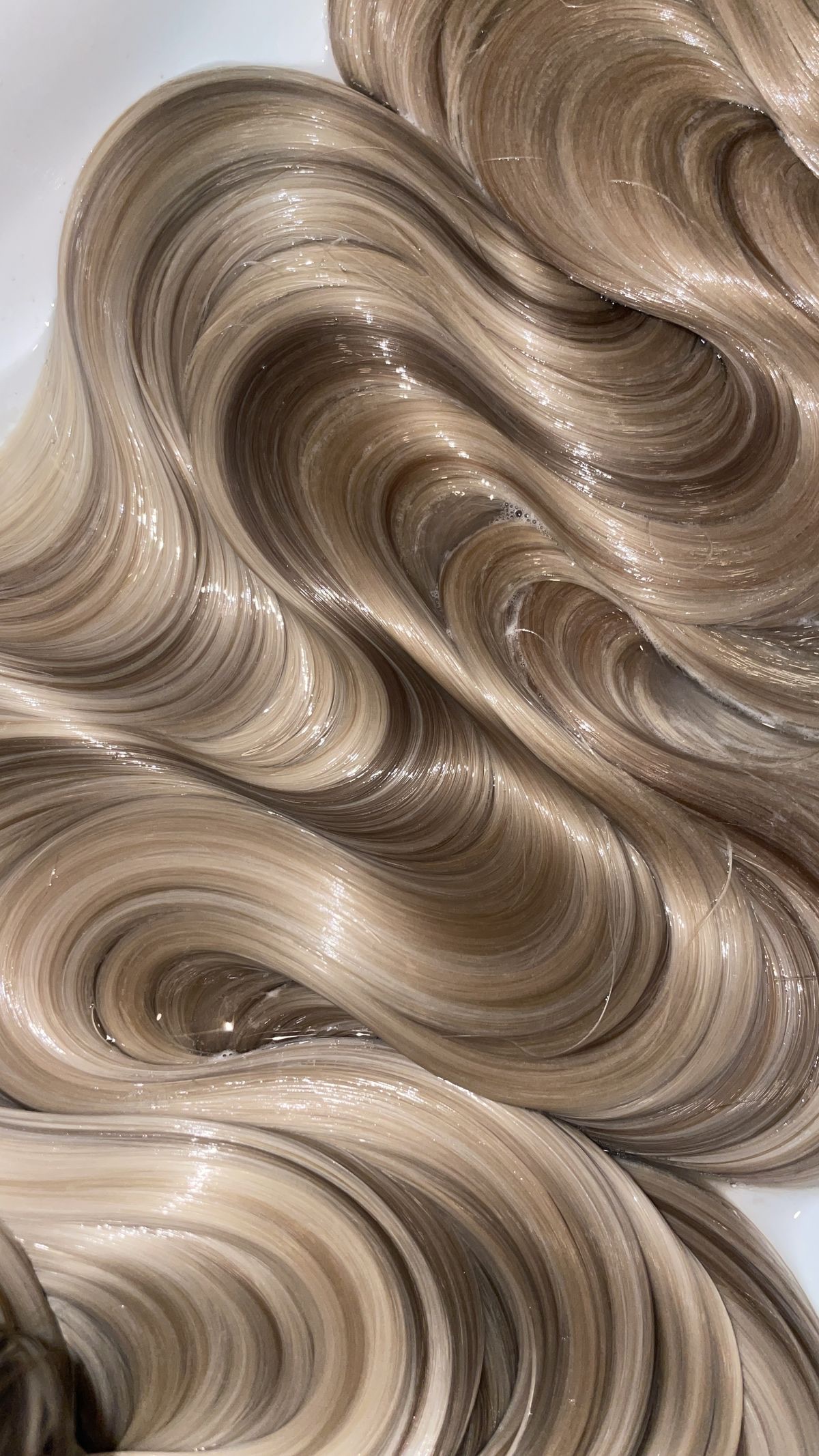 Close-up of glossy blonde human hair in soft waves