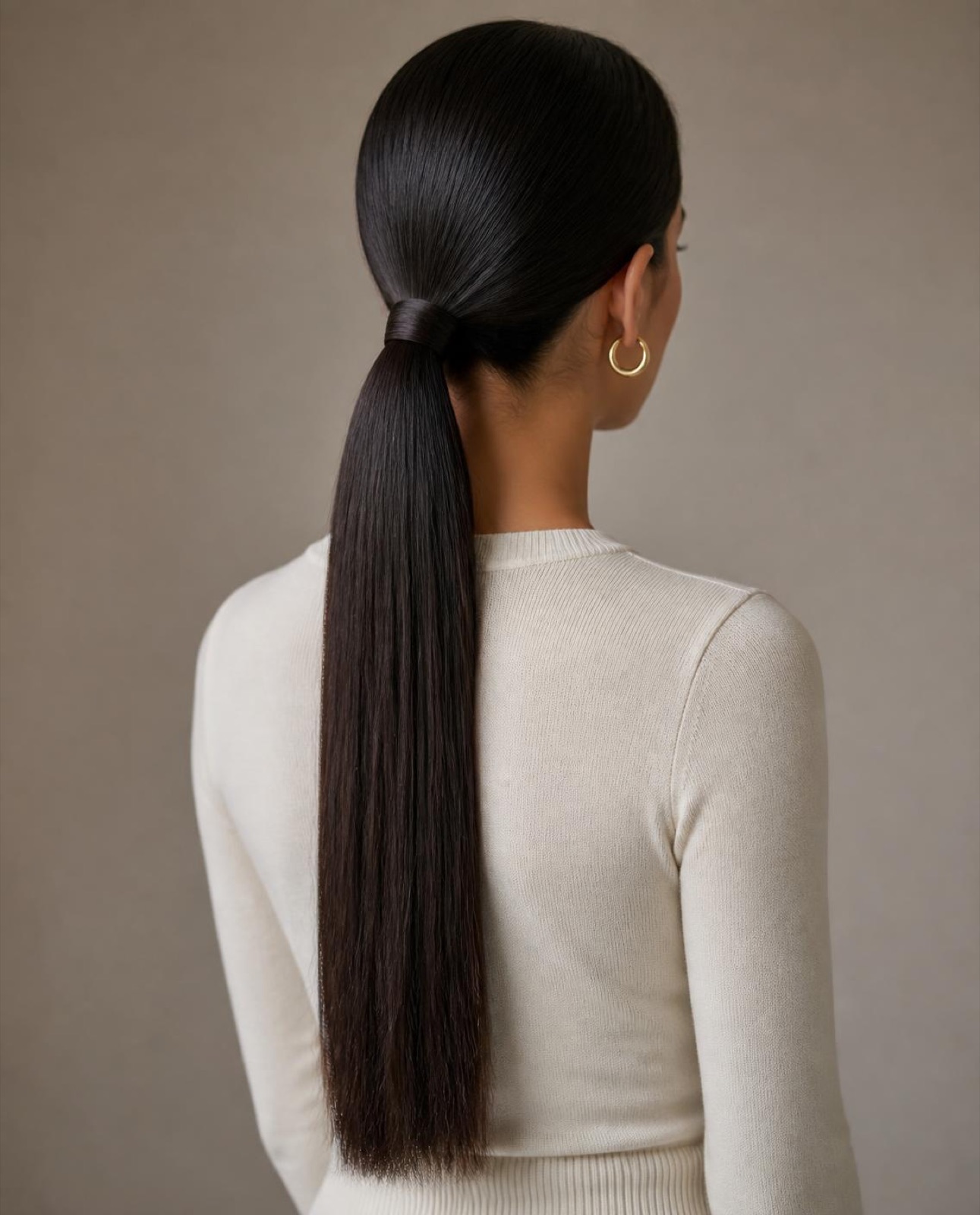 Sleek, low soft-black ponytail seen from behind